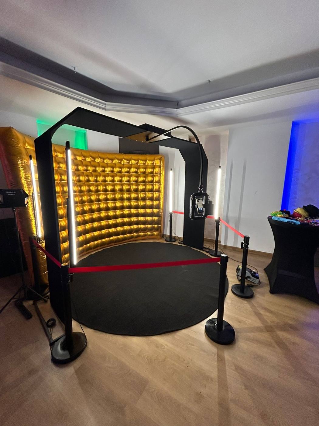 Fotobudka 360° z łukiem w sali, przed złotą ścianką, ze słupkami z czerwoną liną